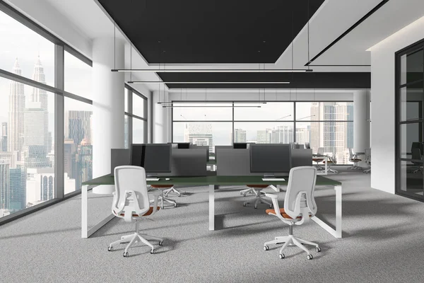 Minimalist office interior with pc monitors on shared desk in row, carpet on floor. Stylish coworking space with glass room, panoramic window on Kuala Lumpur skyscrapers. 3D rendering