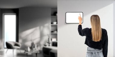 Kadın parmak dokunuşu tablet ekranı duvar bölmesinde, oturma odasının içinde rahatlama yeri var. Ev yönetimi, teknolojiler ve uzaktan kontrol kavramı