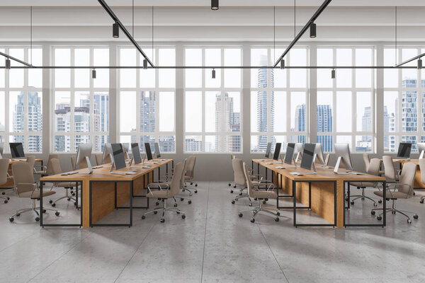 Industrial office interior with pc computers on shared desk in row, tile concrete floor. Stylish coworking zone with panoramic window on Bangkok skyscrapers. 3D rendering