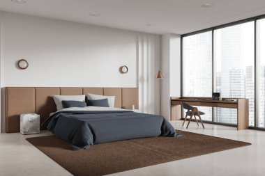 Modern yatak odasının köşesinde beyaz duvarlar, beton zemin, rahat kral yatağı mavi kapaklı ve pencerenin yanında duran ahşap masa. 3d oluşturma