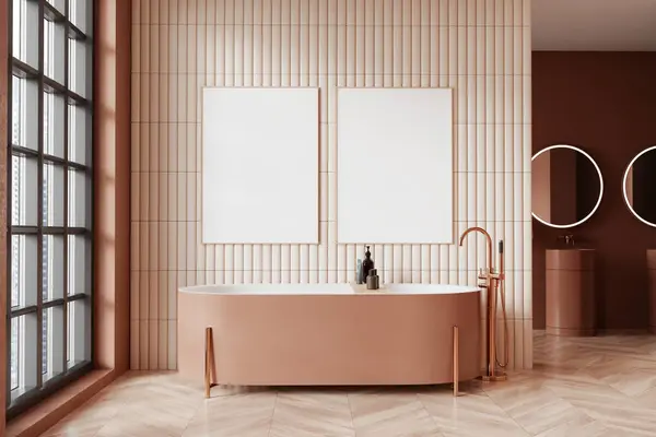 Interior of modern bathroom with beige tiled walls, wooden floor and comfortable beige bathtub standing near window. Two vertical mock up posters. 3d rendering