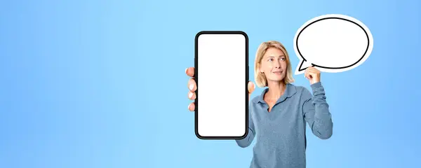 一个快乐的年轻欧洲女人的画像 她站在蓝色的背景上 带着语音泡沫 展示着带有模拟显示的智能手机 传播和广告的概念 — 图库照片