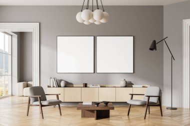 Gri duvarları, ahşap zemini, sehpanın yanında duran rahat gri koltukları ve ahşap şifoniyerin üzerinde asılı iki kare maket posterleri olan modern oturma odasının içi. 3d oluşturma
