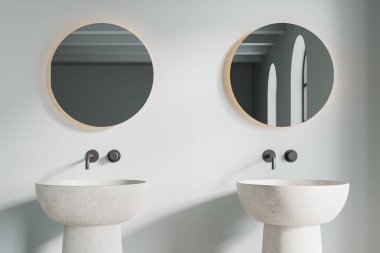 Modern banyonun içinde açık mavi duvarlar ve üzerinde iki tane yuvarlak ayna asılı, serbest ve beyaz çift lavabo. 3d oluşturma
