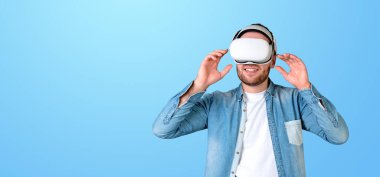 VR kulaklık takan bir adam, elleriyle ayarlıyor, sade mavi bir arka plan, sanal gerçeklik kavramı.