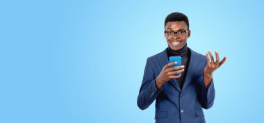 Mutlu siyah işadamı telefonu kullanarak dostça bir el hareketi yapıyor. Boşluk mavisi arkaplanı kopyala İş iletişimi, sosyal medya ve çevrimiçi alışveriş kavramı