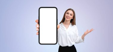 Elinde boş bir ekranla telefonu tutan bir kadın, bir ekran modeli şablonu sunuyor. Gülümsüyor ve el kol hareketi yapıyor, hafif bir arkaplanla.