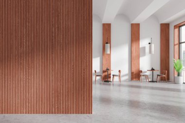 Solunda ahşap duvar paneli olan modern bir kafe. Parlak, minimalist bir alana sahip beton zeminde parlak masalar ve sandalyeler. 3B Hazırlama