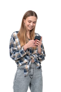 Akıllı telefon kullanan, ekose gömlek ve kot giyen, beyaz arka planda izole edilmiş, iletişim konsepti olan gülümseyen bir kadın.