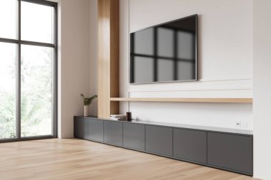 Duvara monte edilmiş düz ekran bir televizyonun, ahşap aksanlı minimalist dekorun ve yeşil manzaralı geniş bir pencerenin olduğu modern oturma odası. 3B Hazırlama