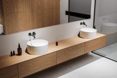 Ahşap tezgahta iki yuvarlak lavabosu, büyük aynaları ve ahşap dolapları olan modern bir banyo. Minimalist tasarım, hafif arkaplan. 3B Hazırlama