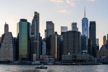 Alacakaranlıkta New York şehrinin ufuk çizgisi rıhtımdan yansıyan ışığı yansıtan yüksek binalarla birlikte. Şehir manzarası kavramı