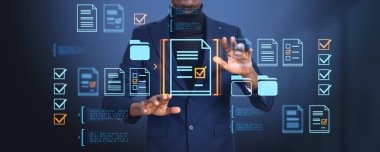 Siyah işadamı elleri sanal ekrana dokunur, belge yönetim sistemi hologramına. Bağlı dosyaların, klasörlerin ya da sözleşmelerin simgeleri parlıyor. Çevrimiçi veritabanı kavramı ve arama