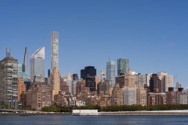 New York 'un gökdelenlerin ve binaların bulunduğu gökdelenlerin ve açık mavi bir gökyüzü ve bir rıhtımın bulunduğu panoramik bir manzara. Şehir manzarası kavramı