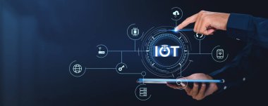 Bir el, IoT bağlantılarını ve cihazlarını temsil eden dijital bir arayüzle karanlık bir arkaplanda etkileşime girer. Küresel bağlantı ve teknoloji kavramı