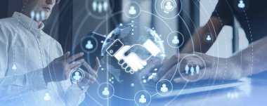 İş adamları cihazları kullanıyor, birlikte çalışıyorlar. Dünya küresiyle parlayan el sıkışma hologramı Hud ve insanlar anlaşma, ortaklık ve işbirliği kavramının simgeleri