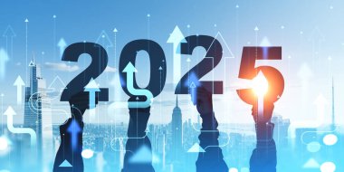 2025 rakamlarını tutan eller parlak bir siluet arkaplanına karşı, yeni başlangıçları simgeliyor.