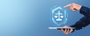 Bir kişi, üzerinde mavi bir arkaplanda dijital hukuk ve hukuk hizmetlerini sembolize eden, parlayan bir adalet ölçeği simgesi olan bir tablet tutuyor. Hukuk teknolojisi ve adalet yeniliği kavramı