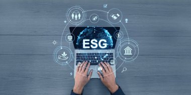 Dizüstü bilgisayarda ESG mesajı ve tahta masada simgeler var. Dijital, fütüristik tarzda. Çevre, sosyal ve yönetim kavramlarını temsil eder