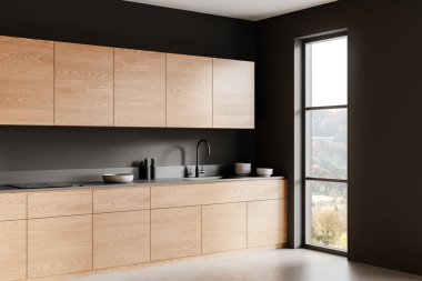 Ahşap dolaplar, siyah tezgahlar ve büyük bir pencereden gelen doğal ışık içeren gösterişli modern mutfak. Minimalist tasarım. 3B Hazırlama