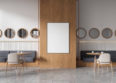 Hafif ahşap panelli, yuvarlak aynalı ve küçük masalı minimalist bir kafe. Gri koltuklar ve nötr tonlar. Duvarda boş bir poster çerçevesi var. 3B Hazırlama