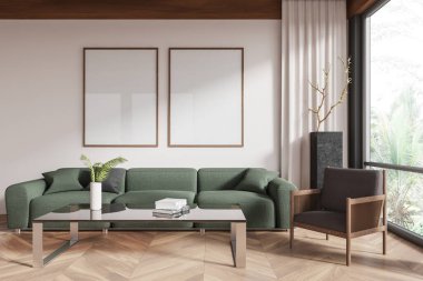 Yeşil bir kanepe, sehpa ve koltuğun üzerindeki beyaz bir duvarda, tahta çerçeveli iki boş poster. Oturma odası iç dekorasyon konsepti. 3B Hazırlama.