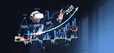VR kulaklık takan bir adam, 2025 'e kadar olan tahminleri gösteren fütüristik bir finansal tabloyla etkileşime geçiyor. Koyu arkaplan, pazar eğilimleri kavramı