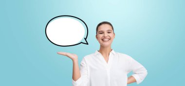 Beyaz tişörtlü, gülümseyen bir kadın açık mavi arka planda boş bir konuşma balonunun altında el kol hareketi yapıyor. İletişim ya da fikir kavramı