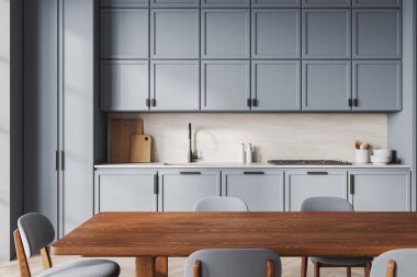 Gösterişli modern mutfak, mavi dolaplar, ahşap tezgah aksanları, ve minimalist dekorlar, rahat bir yemek masası ve gri sandalyeleri var. 3B Hazırlama.