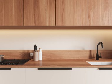 Ahşap dolapları ve tezgahı olan minimalist mutfak manzarası. Ilık ışıklandırma, temiz lavabo ve gaz sobası. Çağdaş tasarım zarafeti. 3B Hazırlama