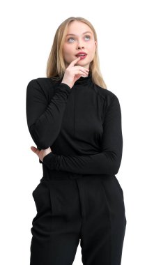 Süveter ve pantolon giyen genç bir kadın eli çenesinde, beyaz bir arka planda izole bir şekilde düşünceli bir şekilde poz veriyor.