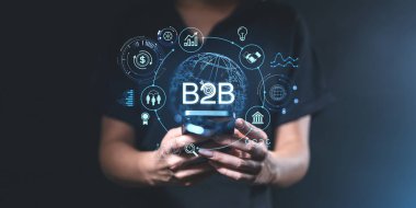 Parlak bir B2B ağ konsepti ve etrafında simgeler olan bir akıllı telefonu tutan kişi. Karanlık arka plan. Çevrimiçi iş başarısı kavramı