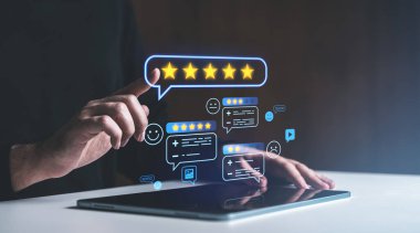 Eller karanlık bir ortamda tablet üzerinde parlayan beş yıldızlı yorum simgeleri ile etkileşime girer, çevrimiçi geri bildirim, anketler ve müşteri memnuniyetini gösterir