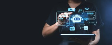 Dijital tabletle etkileşime giren bir kişi koyu arkaplanda parlayan bir sohbet robotu simgesi barındırır. Yapay Zeka destekli sohbet yardımı kavramı