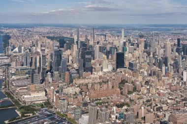 New York şehrinin gökdelenleri, konut binaları ve parçalı bulutlu bir gökyüzünün altındaki yeşilliklerin panoramik görüntüsü.