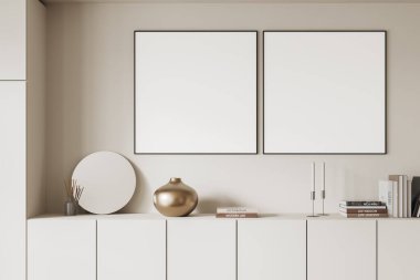 Dolabın üstündeki duvarda vazo, kitap ve mumlar gibi modern dekorları olan iki boş çerçeveli poster. Tarafsız tonlar, asgari tasarım konsepti. 3B Hazırlama.
