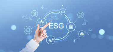 Mavi arkaplandaki ESG dijital simgelerine el ile işaret ederek sürdürülebilirliği, yönetimi ve çevresel sorumluluğu sembolize ediyor
