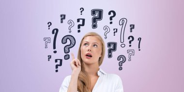 Merakı ya da karar verme mekanizmasını temsil eden soru işaretleriyle çevrili düşünceli bir kadın. Pastel arka plan yaratıcı düşünce kavramını vurguluyor