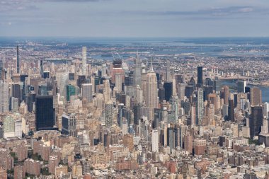 Manhattan 'ın ikonik gökdelenlerinin hava fotoğrafı, New York şehir merkezi, ABD, nehirler ve şehir çevresi, bulutlu bir gökyüzü altında