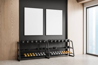 Modern jimnastik salonu içinde iki tane çerçeveli boş poster var. Koyu renkli bir duvarda, düzgünce düzenlenmiş bir halterin üzerinde. Geniş pencere doğal ışığın içeri girmesine izin veriyor. 3B Hazırlama.
