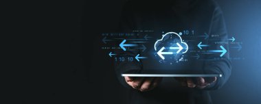 Eller bulut depolama ve veri aktarım simgeleri, parlayan mavi oklar ve uzak ağ erişimini sembolize eden koyu arkaplan üzerinde ikili kod içeren bir tablet tutuyor.