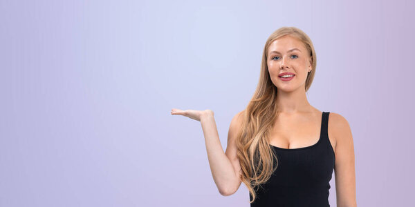 Счастливая женщина с длинными светлыми волосами в черном топе, с открытым жестом на пастельно-фиолетовом фоне, концепция презентации