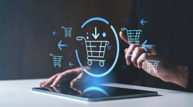 Eller holografik alışveriş arabası simgelerini gösteren bir tabletle etkileşime giriyor, e-ticareti ve karanlık bir arkaplanda çevrimiçi perakende işlemlerini sembolize ediyor.