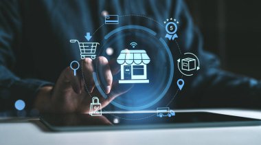 Bir tabletle el etkileşimi, karanlık bir arka planda holografik online alışveriş ikonları sergiliyor. E-ticaret, perakende ve dijital işlemler kavramı