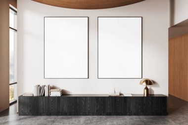 Minimalist iç mekan, karanlık bir ahşap dolabın üstündeki aydınlık duvarda iki boş poster, kitaplar ve altın bir lambayla süslenmiş. 3B Hazırlama