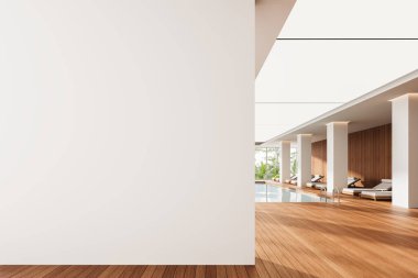 Modern kapalı havuzda ahşap döşemeli ve şezlonglu tasarım sunumu için boş bir duvar. Parlak ışıklandırma ve doğal elementler atmosferi güçlendirir. 3B Hazırlama.