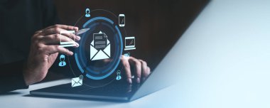Bulanık bir arka planda holografik e-posta arayüzü olan bir dizüstü bilgisayar kullanan bir iş adamı. Dijital pazarlama, e-posta iletişimi ve çevrimiçi mesajlaşma kavramı