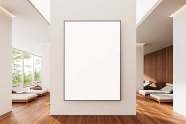 Ahşap döşemeleri ve şezlongları olan parlak, modern bir iç mekânda temiz beyaz bir duvara boş dikey poster çerçevesi. Büyük pencereler doğal bir manzara sunar. 3B Hazırlama.