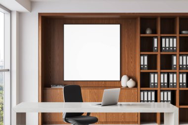 Çalışma odası, ahşap duvarda boş çerçeveli poster, dizüstü bilgisayarlı masa, sandalye ve klasörlü raflar. Parlak, temiz iç mekan konsepti. 3B Hazırlama.