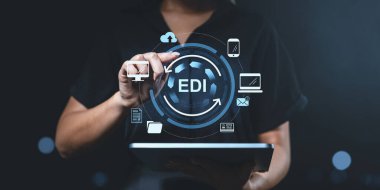 İş kadını EDI teknolojisini fütüristik dijital simgeler, parlayan arayüz ve koyu bulanık arkaplan, otomasyon kavramı olan bir tablette kullanıyor.